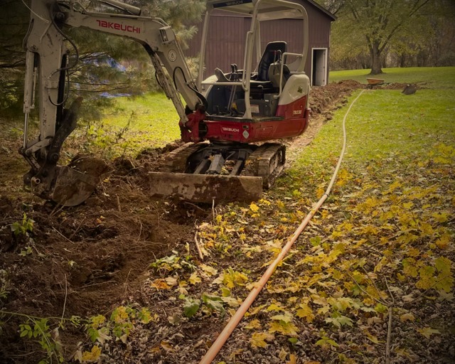 Mini excavator cutting backyard trench