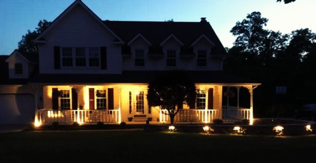 Warm landscape lighting across house frontage